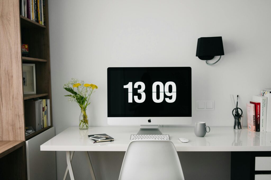 pexels-photo-265129-265129 A minimalist workspace featuring a computer displaying time, organized bookshelves, and stylish decor.